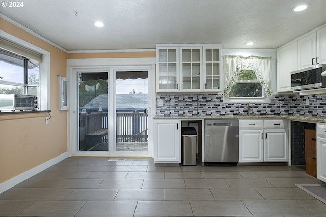 kitchen with crown molding, appliances with stainless steel finishes, white cabinets, and tasteful backsplash