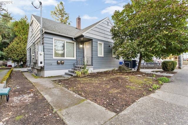 bungalow-style home featuring roof with shingles and a chimney