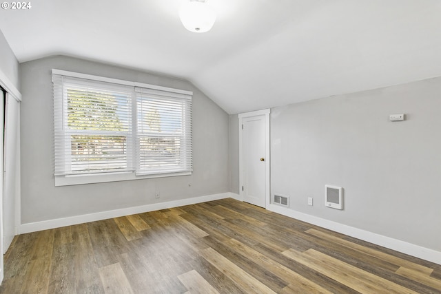 additional living space featuring vaulted ceiling, wood finished floors, visible vents, and baseboards