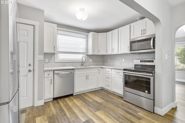 kitchen with white cabinets, appliances with stainless steel finishes, light countertops, and a sink