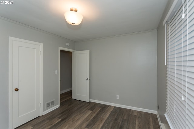 unfurnished bedroom featuring baseboards, visible vents, dark wood-type flooring, and ornamental molding