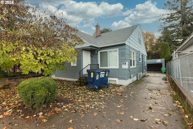 view of front of house featuring roof with shingles, a chimney, and fence