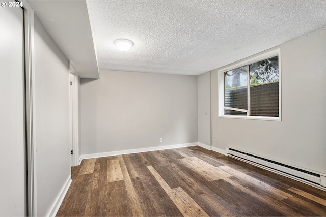 spare room with dark wood-style flooring, baseboards, a textured ceiling, and baseboard heating