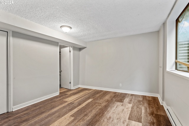 unfurnished room featuring wood-type flooring, a textured ceiling, and a baseboard radiator