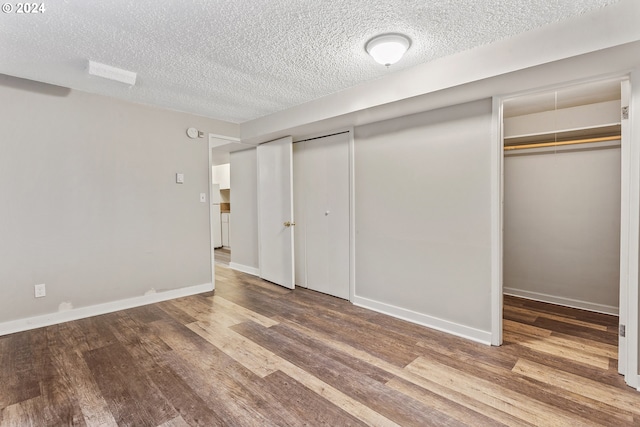 unfurnished bedroom featuring a textured ceiling, wood finished floors, and baseboards