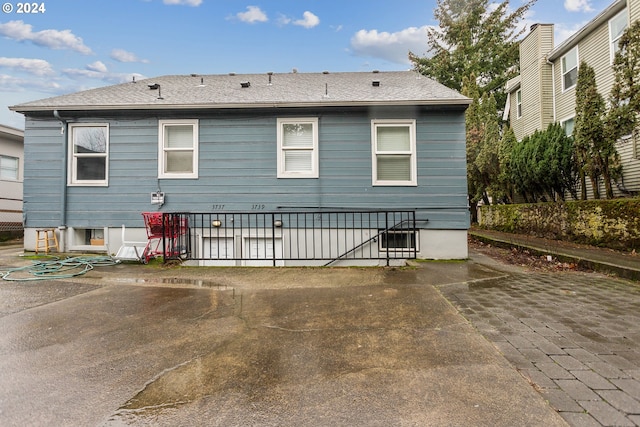 rear view of house with a patio area and roof with shingles