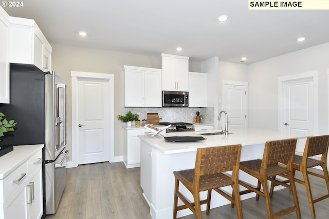 kitchen with a kitchen island with sink, sink, white cabinets, and appliances with stainless steel finishes