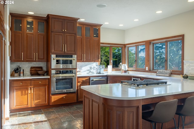 kitchen with appliances with stainless steel finishes, sink, a kitchen breakfast bar, and backsplash