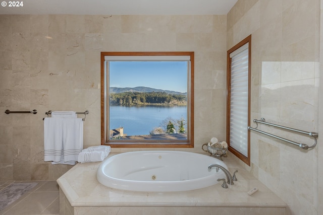 bathroom with tiled tub, tile walls, and a water and mountain view