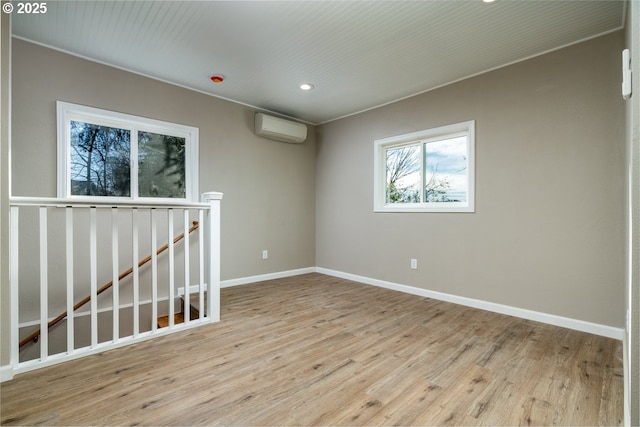 spare room featuring a wall mounted air conditioner and light hardwood / wood-style floors