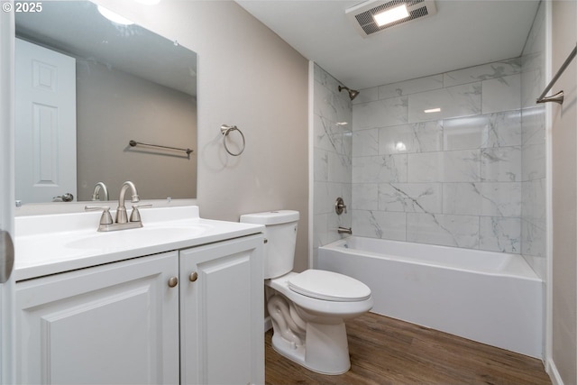 full bathroom with hardwood / wood-style flooring, tiled shower / bath, vanity, and toilet