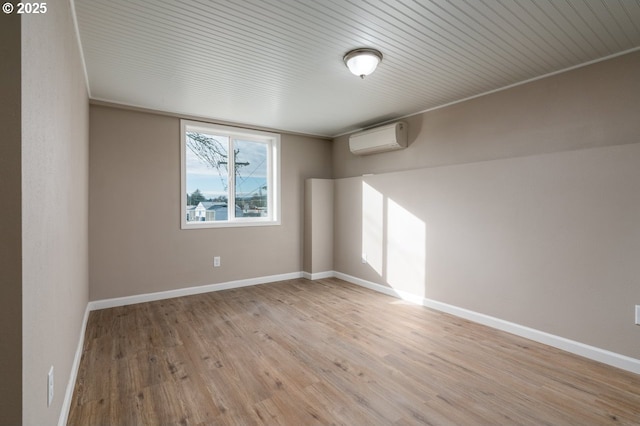 unfurnished room featuring a wall unit AC and light hardwood / wood-style flooring