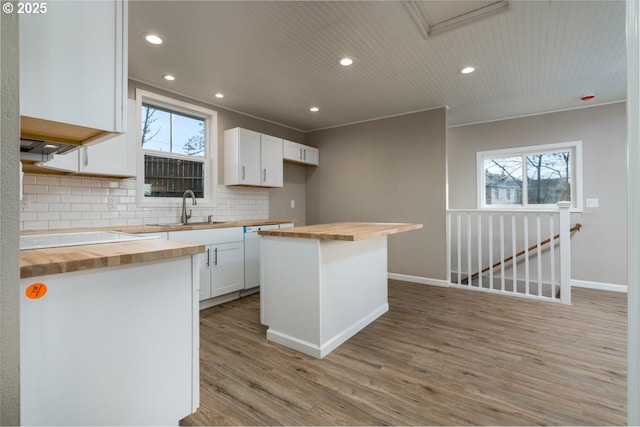 kitchen featuring butcher block counters, sink, white cabinets, and a kitchen island