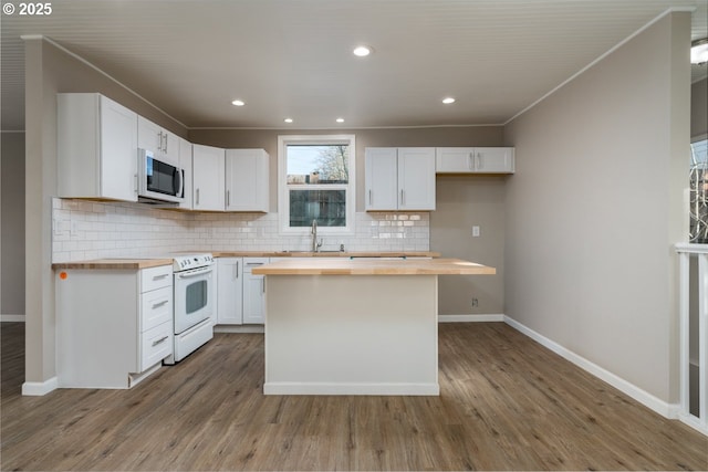 kitchen featuring white electric range oven, wooden counters, a center island, decorative backsplash, and white cabinets