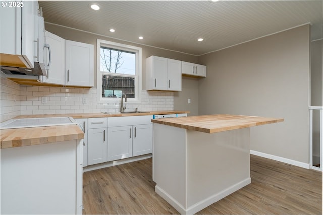 kitchen with white cabinetry, a kitchen island, sink, and wooden counters