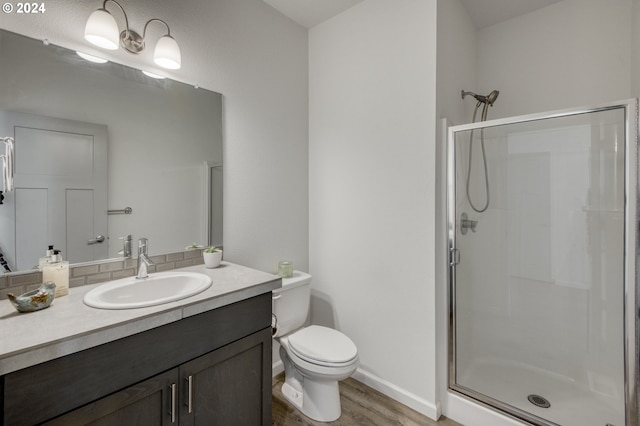 bathroom with hardwood / wood-style flooring, a shower with door, vanity, and toilet