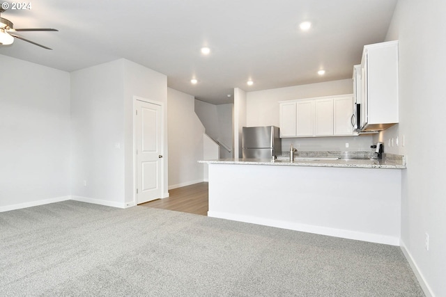 kitchen featuring light stone countertops, white cabinets, stainless steel appliances, and light colored carpet