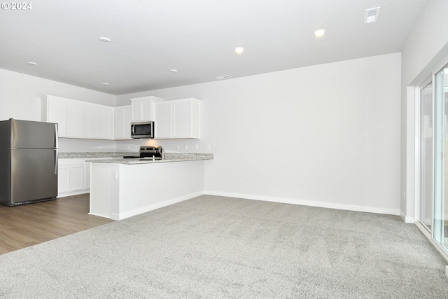 kitchen featuring kitchen peninsula, stainless steel appliances, white cabinetry, and plenty of natural light