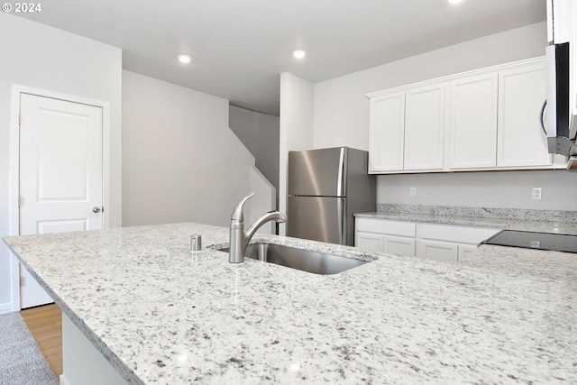 kitchen with sink, light wood-type flooring, light stone counters, white cabinetry, and stainless steel appliances