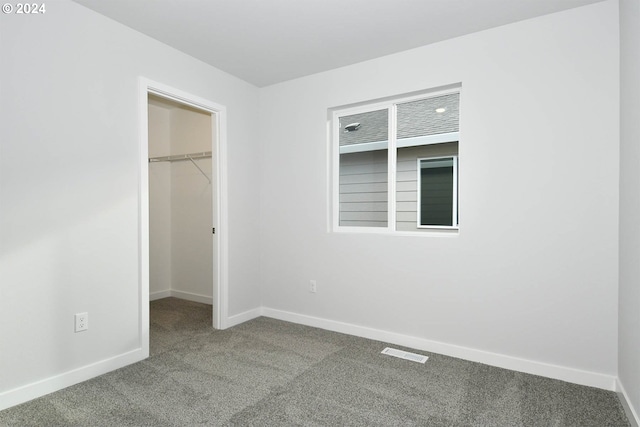 unfurnished bedroom with carpet flooring, a spacious closet, and a closet