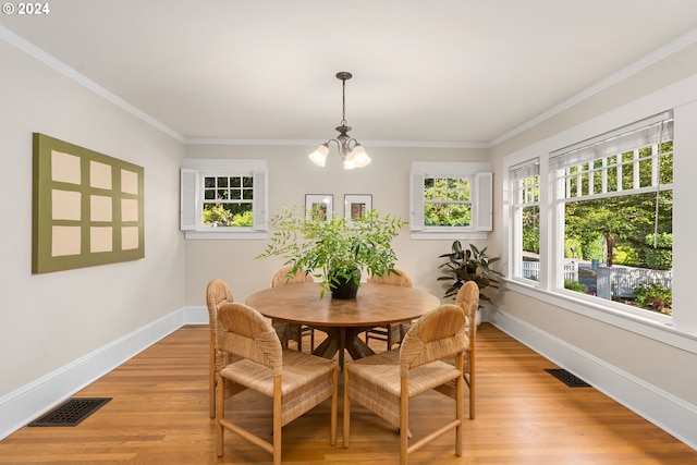 dining space featuring ornamental molding, an inviting chandelier, and light hardwood / wood-style floors