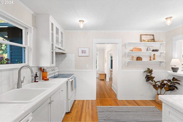 kitchen with range with electric cooktop, light wood-type flooring, tile countertops, and white cabinets