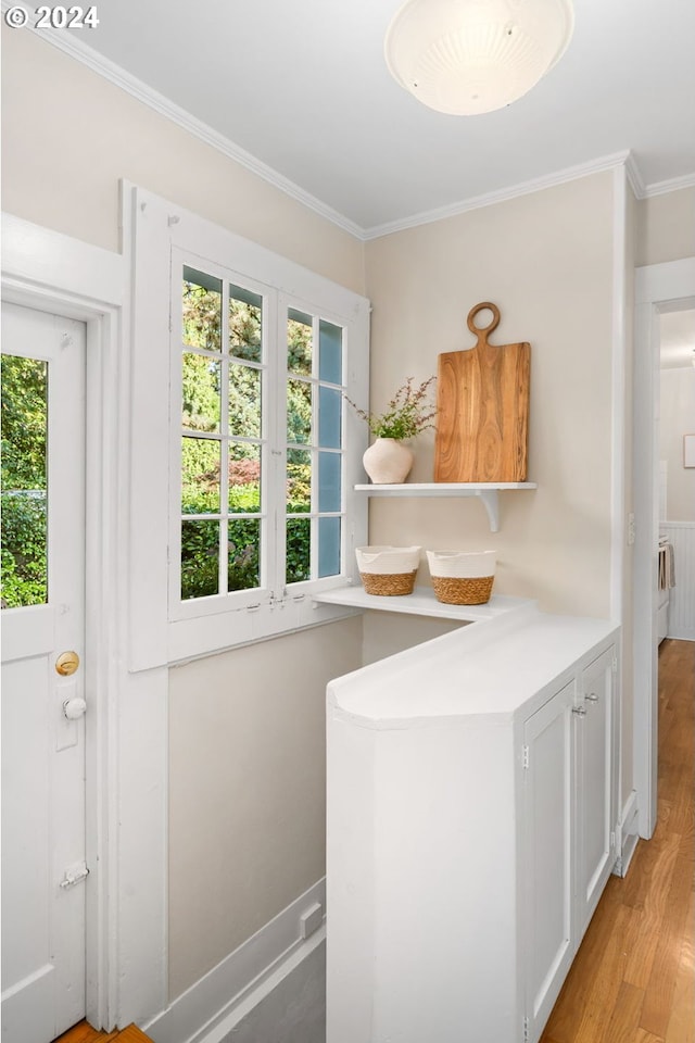 interior space with crown molding, light hardwood / wood-style flooring, and white cabinetry