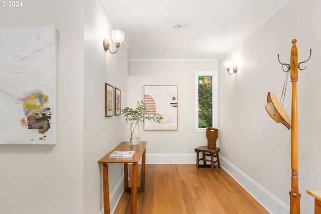 corridor with ornamental molding and light hardwood / wood-style floors