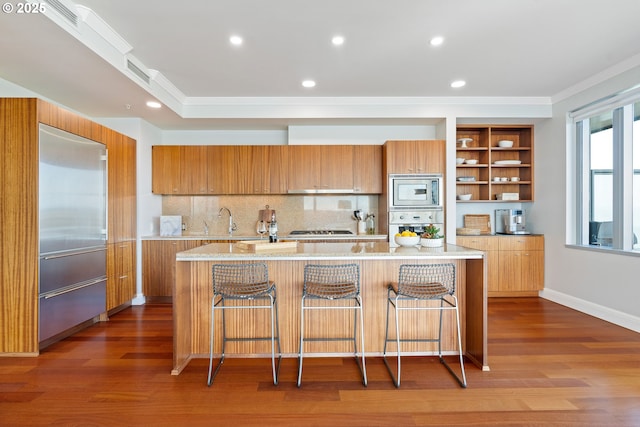 kitchen featuring modern cabinets, brown cabinets, wood finished floors, and built in appliances