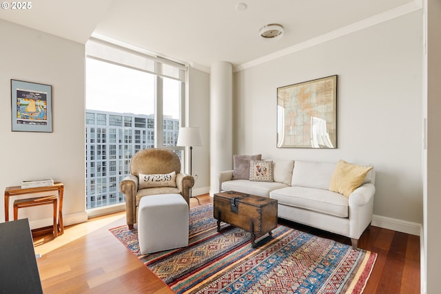 living area with expansive windows, ornamental molding, wood finished floors, and baseboards