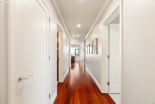 corridor featuring dark wood-style floors, recessed lighting, baseboards, and crown molding