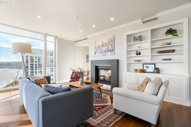 living room with visible vents, wood finished floors, crown molding, floor to ceiling windows, and a multi sided fireplace