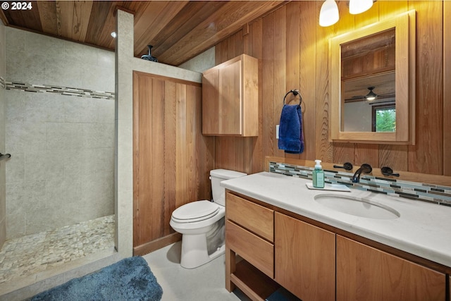 bathroom with a tile shower, wooden ceiling, toilet, wooden walls, and vanity