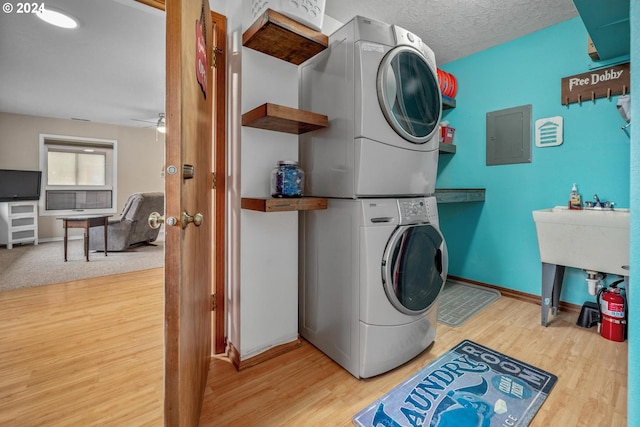 laundry area with hardwood / wood-style floors, ceiling fan, stacked washer and dryer, and a textured ceiling