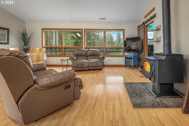 living room with hardwood / wood-style flooring, a wood stove, and vaulted ceiling