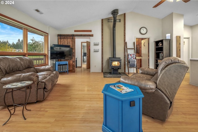 living room with lofted ceiling, ceiling fan, light wood-type flooring, and a wood stove