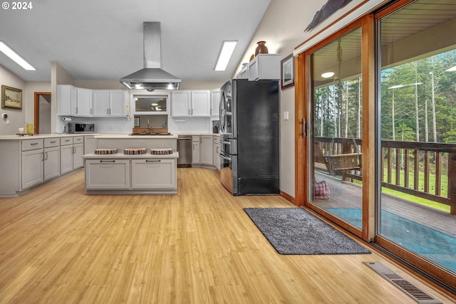 kitchen featuring light wood-type flooring, stainless steel appliances, sink, exhaust hood, and a kitchen island