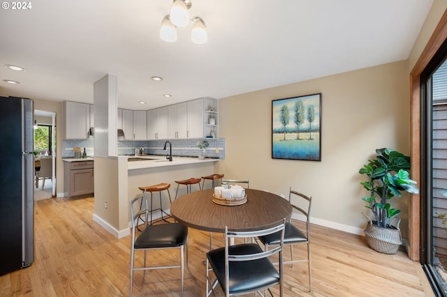 dining area featuring an inviting chandelier, sink, and light hardwood / wood-style floors