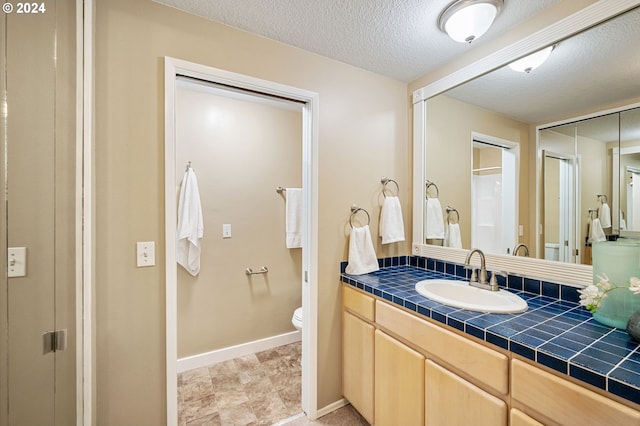 bathroom featuring toilet, a textured ceiling, and vanity