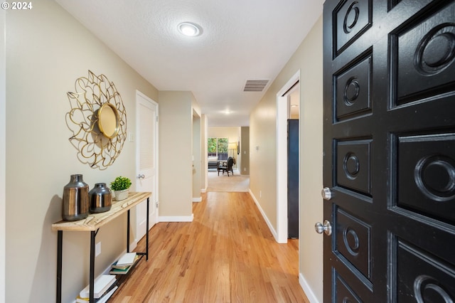 corridor featuring light hardwood / wood-style flooring and a textured ceiling