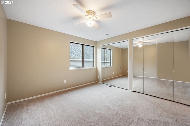 unfurnished bedroom featuring light carpet, multiple closets, and ceiling fan