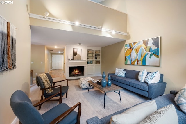 living room featuring carpet floors, a large fireplace, and built in shelves