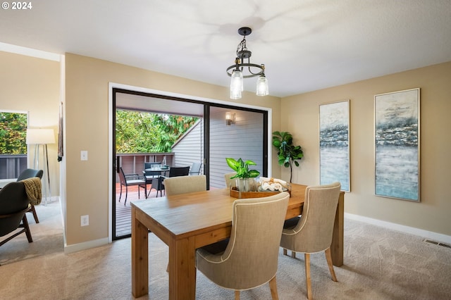 dining area with a notable chandelier and light colored carpet