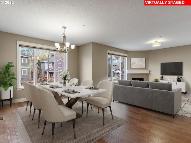 dining room featuring a chandelier, light wood-style floors, visible vents, and a textured ceiling