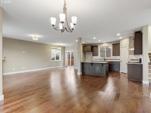 kitchen featuring a notable chandelier, open floor plan, light countertops, a kitchen island, and wood finished floors