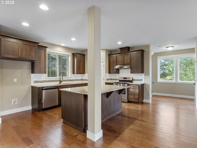 kitchen with dark brown cabinetry, a sink, backsplash, and appliances with stainless steel finishes