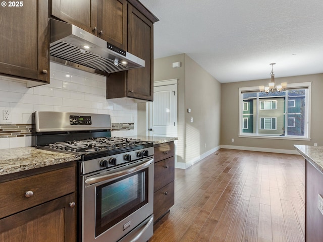 kitchen featuring tasteful backsplash, baseboards, gas stove, dark brown cabinets, and exhaust hood