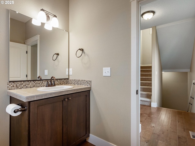 bathroom featuring tasteful backsplash, wood finished floors, and vanity