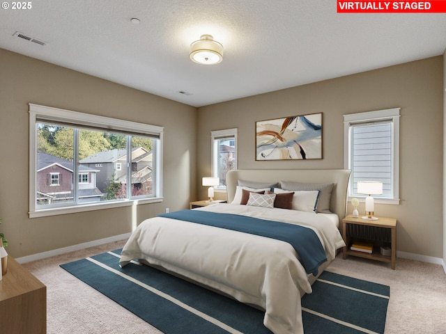 bedroom featuring carpet, visible vents, baseboards, and a textured ceiling