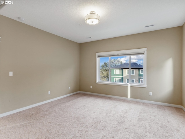 carpeted empty room featuring visible vents and baseboards